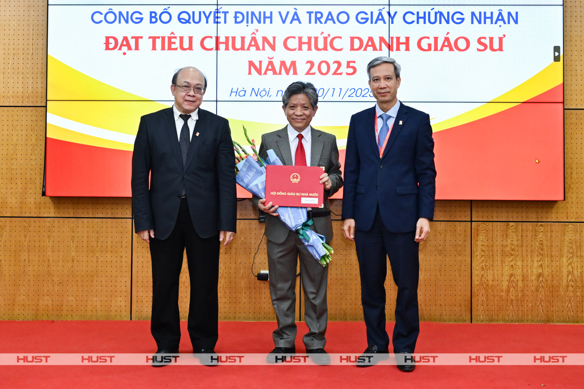 PGS Huỳnh Quyết Thắng - Giám đốc Đại học Bách khoa Hà Nội và GS Lê Anh Tuấn - Bí thư Đảng ủy, Chủ tịch HĐĐH ĐHBK Hà Nội trao Giấy Chứng nhận đạt tiêu chuẩn chức danh Giáo sư và tặng hoa chúc mừng nhà giáo Nghiêm Trung Dũng