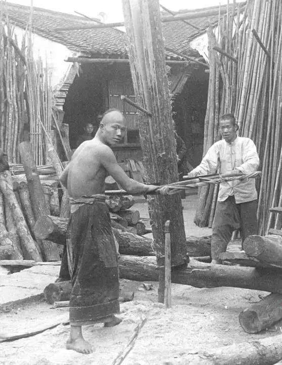   Hai người thợ mộc đang cưa những thân gỗ lớn thành nhiều tấm ván.  