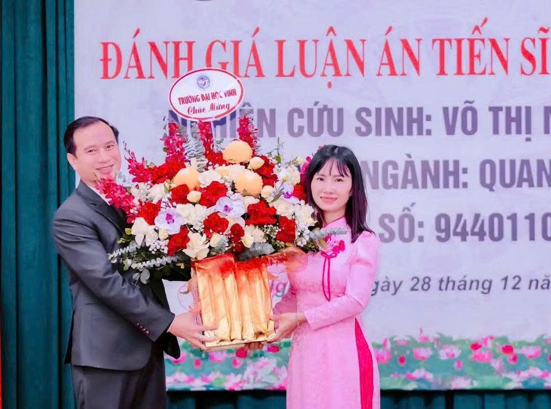    Cô Võ Thị Minh Ngọc nhận hoa chúc mừng từ PGS.TS. Nguyễn Huy Bằng, Hiệu trưởng Trường Đại học Vinh, sau khi bảo vệ thành công luận án Tiến sĩ.  