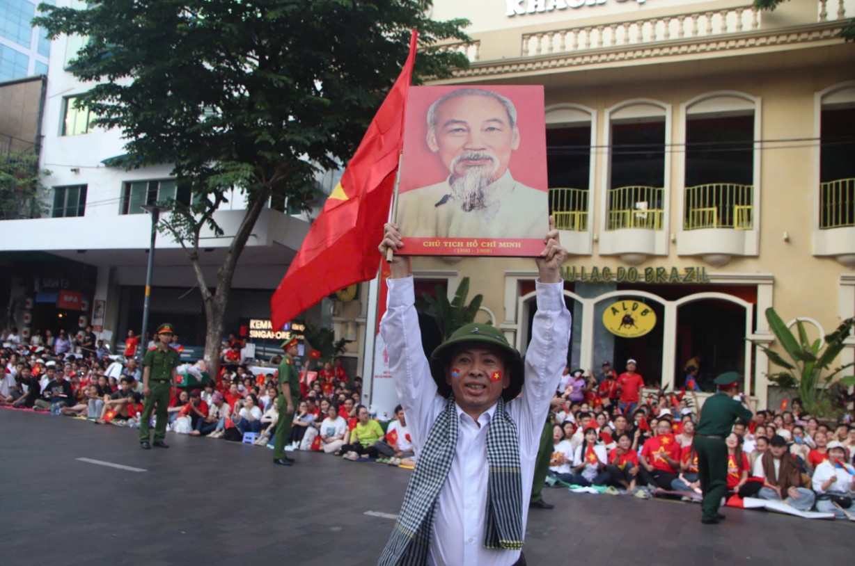 Một người đàn ông kiêu hãnh và tự hào dơ cao ảnh Bác - Ảnh: NLĐ