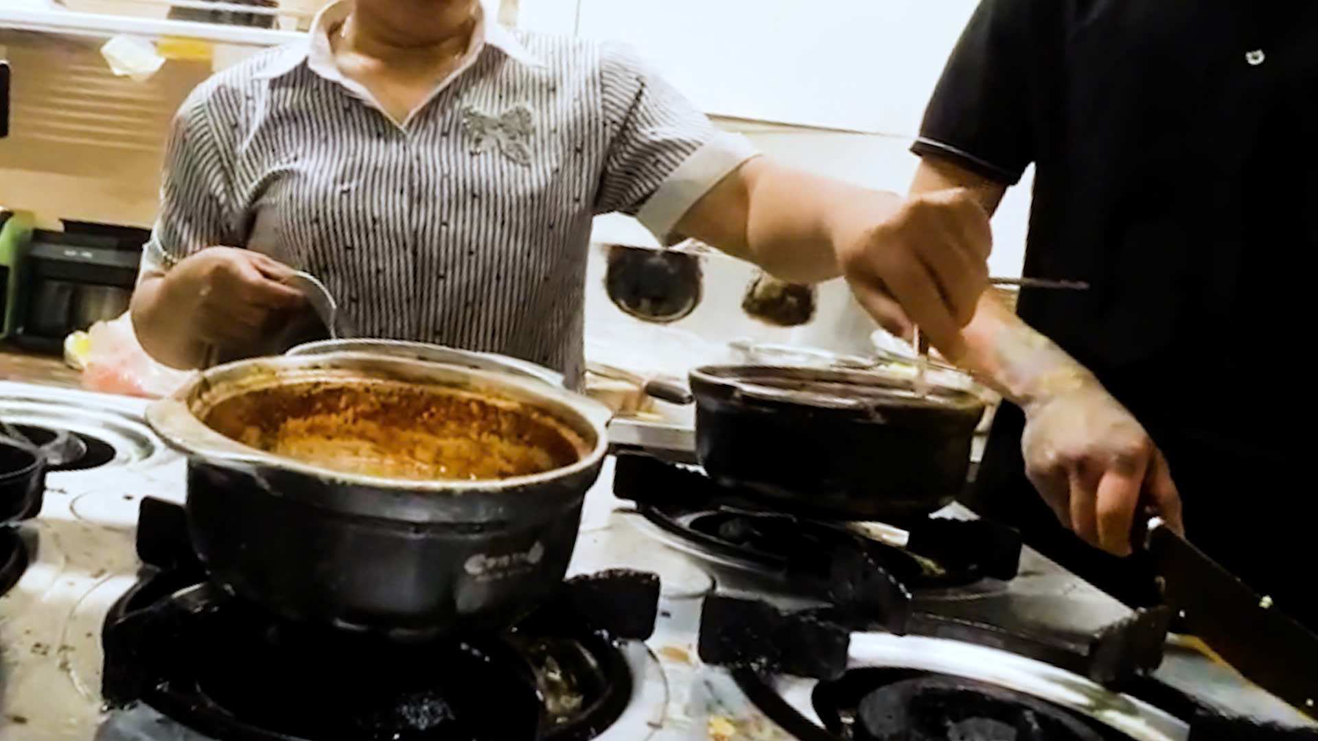 Chủ cửa hàng Cơm thố Bách khoa trực tiếp dùng chìa khóa xe máy “gẩy” dị vật rơi vào thố sốt - Ảnh: Báo Lao Động
