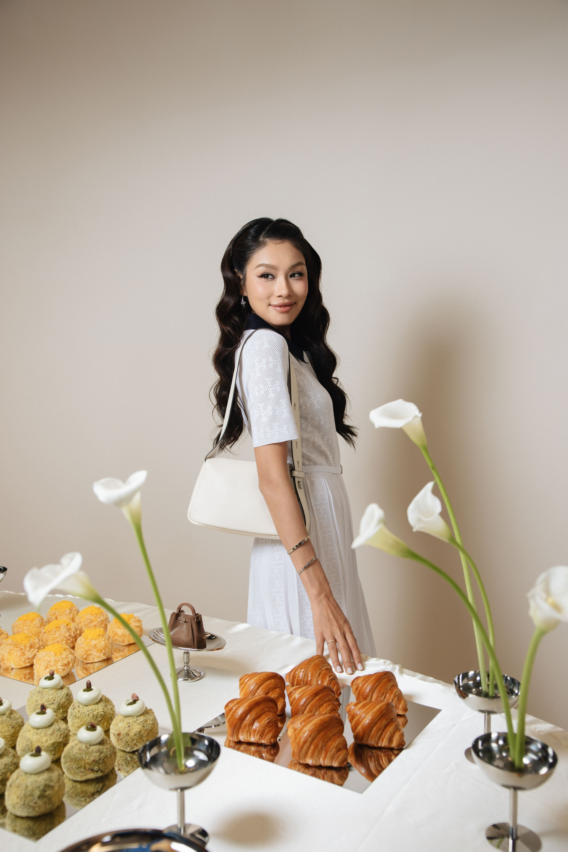 Thảo Nhi Lê chọn hình ảnh thanh lịch với đầm xếp ly họa tiết T Monogram nữ tính. Thiết kế chuyển động mềm mại theo từng bước chân được hoàn thiện cùng túi đeo vai Romy Small màu kem sáng, tạo nên tổng thể tinh giản nhưng vẫn nổi bật nhờ tinh thần nghỉ dưỡng phóng khoáng. Hiện nay, ngoài hoạt động nghệ thuật, cô còn phát triển công việc kinh doanh riêng.