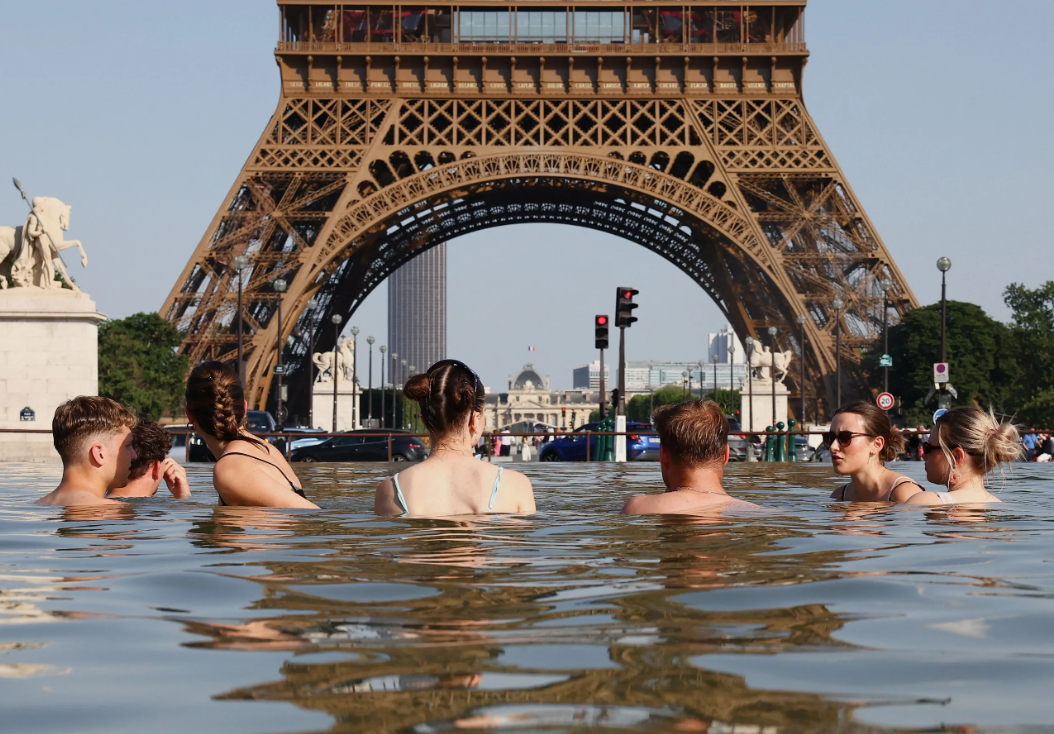 Nhiều người tắm tại đài phun nước gần tháp Eiffel ở thủ đô Paris giữa đợt nắng nóng tại Pháp ngày 22/6 - Ảnh: Reuters