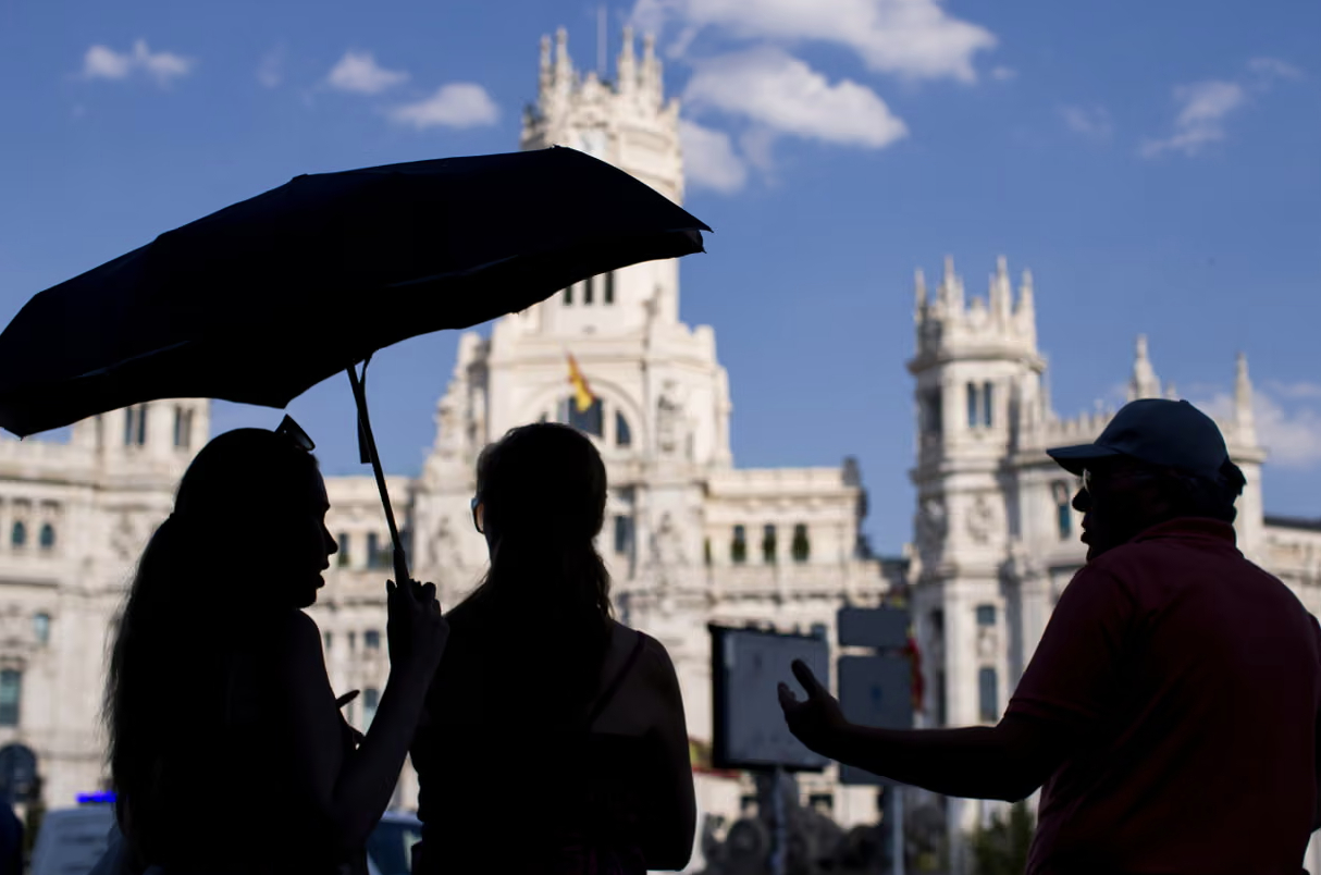 Du khách che nắng bằng ô thăm quan Cung điện Cibeles ở trung tâm Madrid (Tây Ban Nha)