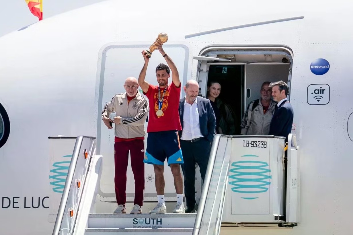 Đội tuyển Tây Ban Nha hạ cánh xuống sân bay Barajas ở Madrid lúc 14h30 ngày 20/7 (giờ địa phương). Ngay khi bước xuống máy bay, đội trưởng Rodri giơ cao chiếc cúp vàng World Cup, trên cổ vẫn đeo tấm huy chương vừa giành được.