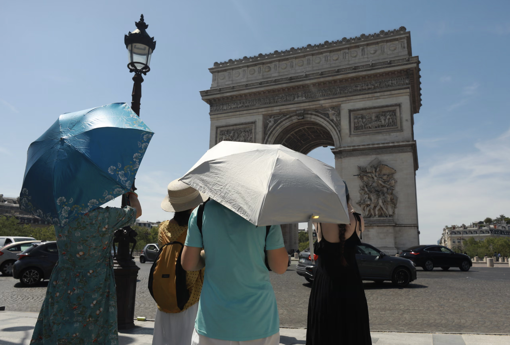Du khách dùng ô che nắng trong đợt nắng nóng gay gắt tại Khải Hoàn Môn ở Paris. Ảnh: Anadolu/Getty Images