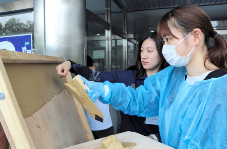 Thợ trát vữa hướng dẫn sinh viên cách trát vữa lên tường (Ảnh: The Japan Times)