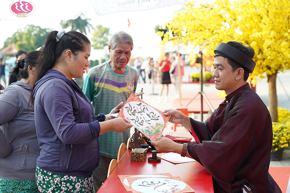 Người dân thích thú tham gia hoạt động xin chữ Ông Đồ tái hiện phong tục quen thuộc vào ngày Tết cổ truyền Việt Nam.