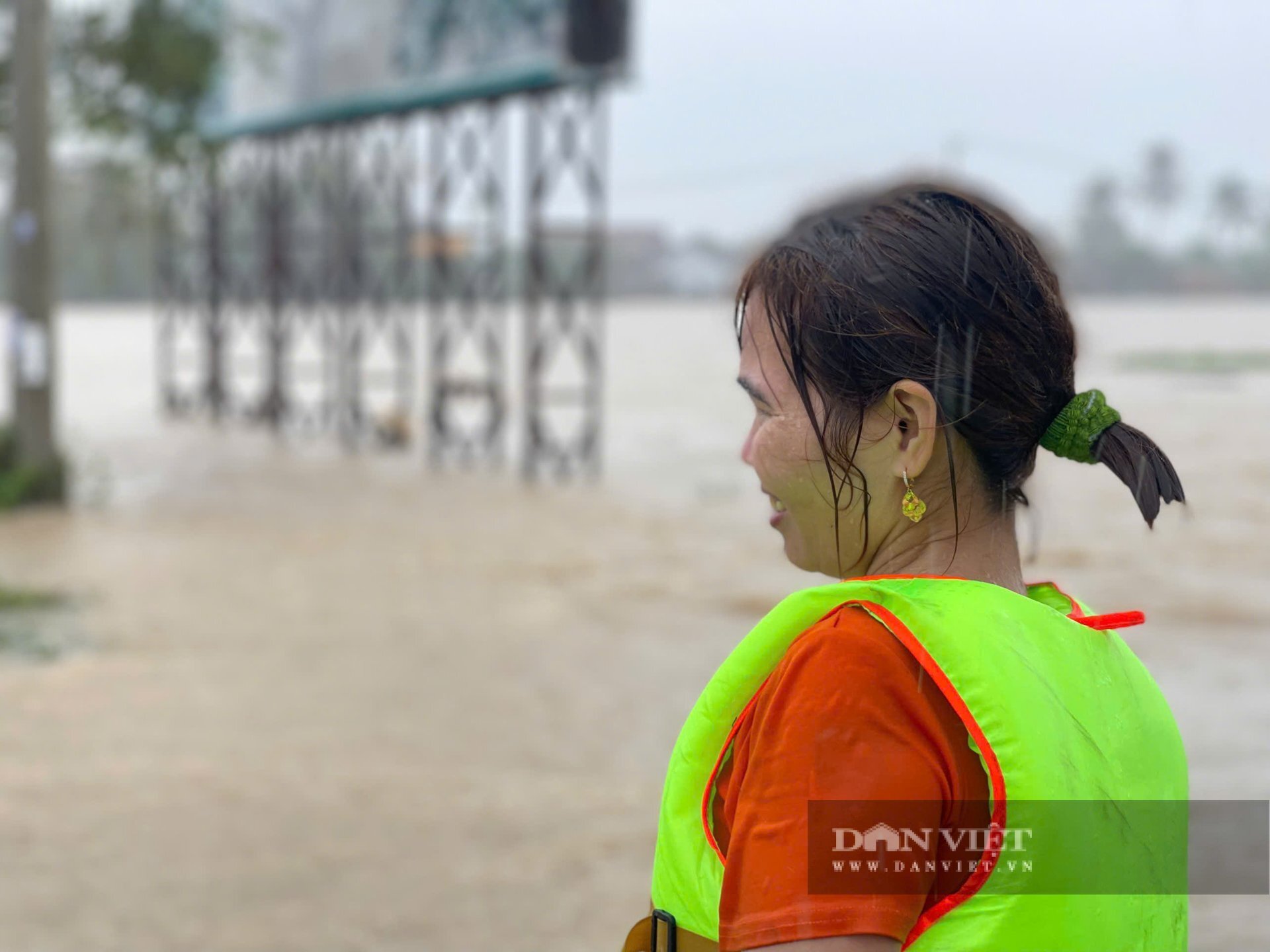 Nhiều phụ nữ nghẹn khóc, nước mắt lẫn trong mưa khi đứng bần thần trên bờ, dõi theo từng chiếc xuồng cứu hộ chờ đợi tin tức của người thân bị mắc kẹt trong vùng ngập. Ảnh: Dân Việt