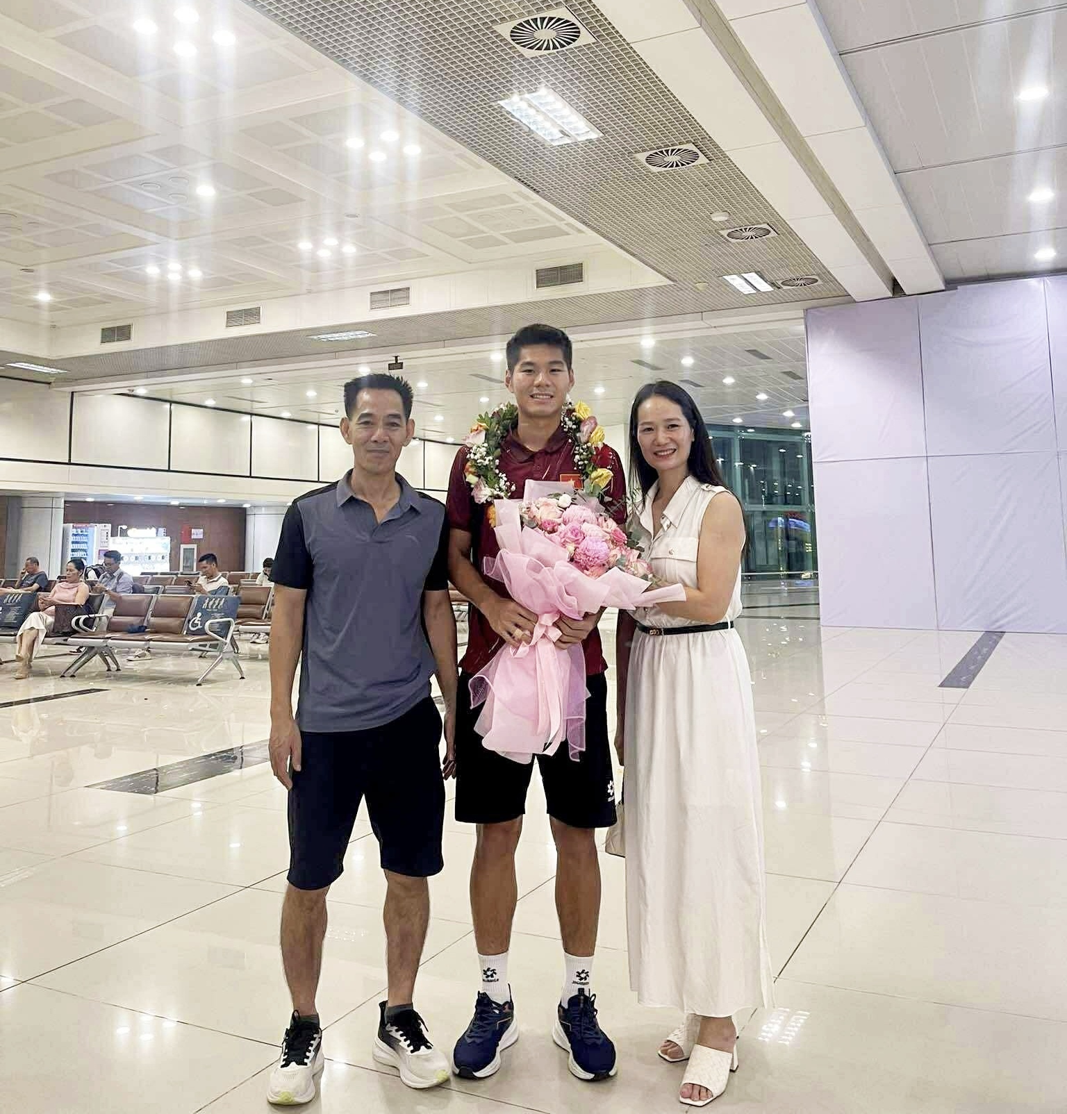 Bố mẹ Hiểu Minh - chú Tiến Quang và cô Thanh Hà - cùng con trai ở sân bay sau khi U22 Việt Nam giành HCV SEA Games 33 (Ảnh: FBNV)