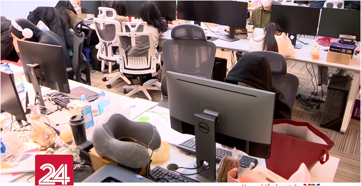 Trên bàn làm việc cũng là những thiết bị văn phòng quen thuộc hoặc đồ dùng cá nhân như gối, ly nước, bánh kẹo,... Ảnh chụp màn hình.