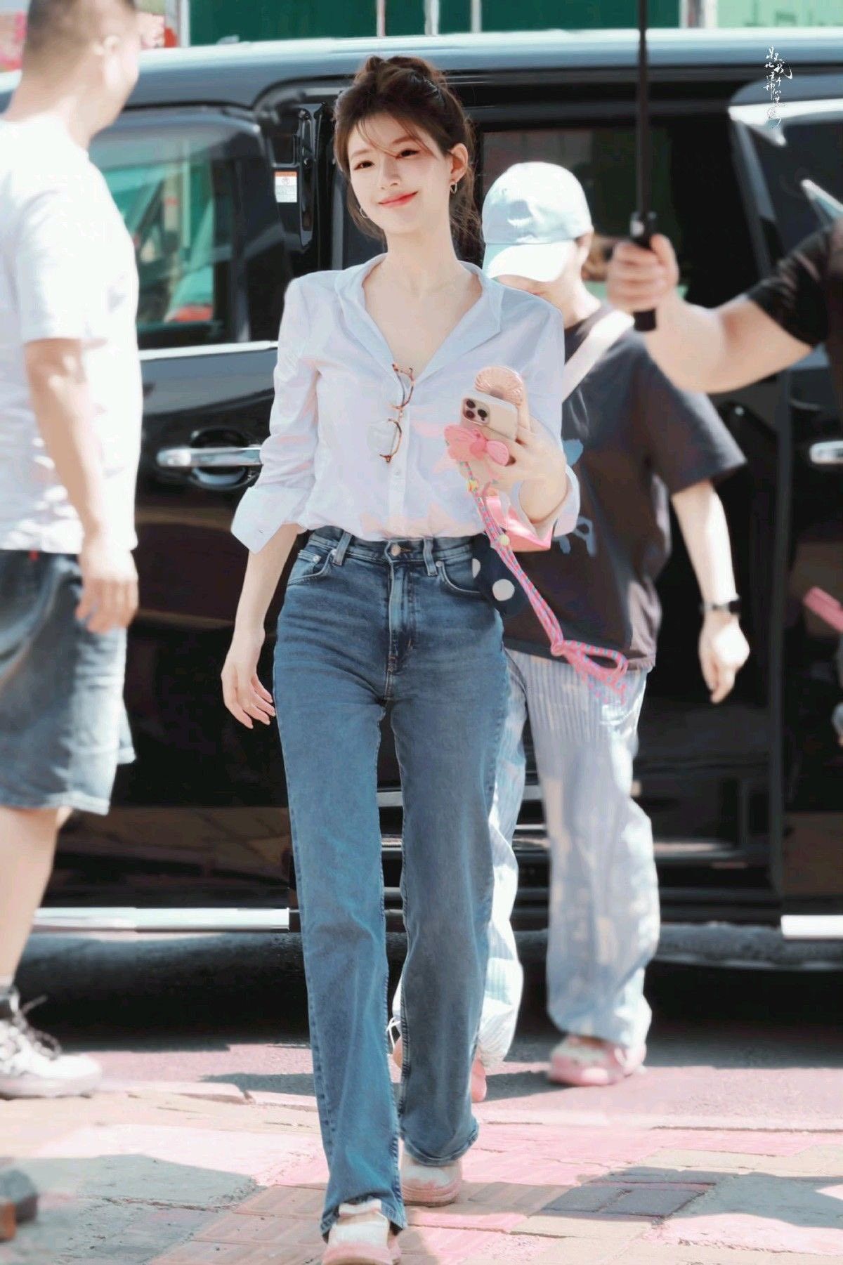 Trong outfit hậu trường từng viral khắp MXH, Triệu Lộ Tư chọn công thức cực đơn giản nhưng rất dễ tạo cảm giác sang: áo sơ mi trắng dáng fit, chất liệu mềm có độ rũ nhẹ thay vì ôm sát, phần cổ mở vài cúc để tổng thể trông thanh thoát và nữ tính hơn. Nữ diễn viên phối cùng quần jeans xanh cạp cao dáng suông nhẹ, ôm vừa phần hông rồi thả thẳng xuống giúp chân nhìn dài và gọn hơn. Phần tóc được búi lơi tự nhiên với vài lọn mái bay nhẹ quanh mặt tạo vibe mềm mại, trong trẻo thay vì quá chỉn chu. Phụ kiện cũng được nàng tiểu hoa giữ ở mức tối giản như khuyên tai nhỏ, kính mắt móc hờ trước ngực áo để tổng thể vẫn trẻ trung lại không bị đơn điệu.