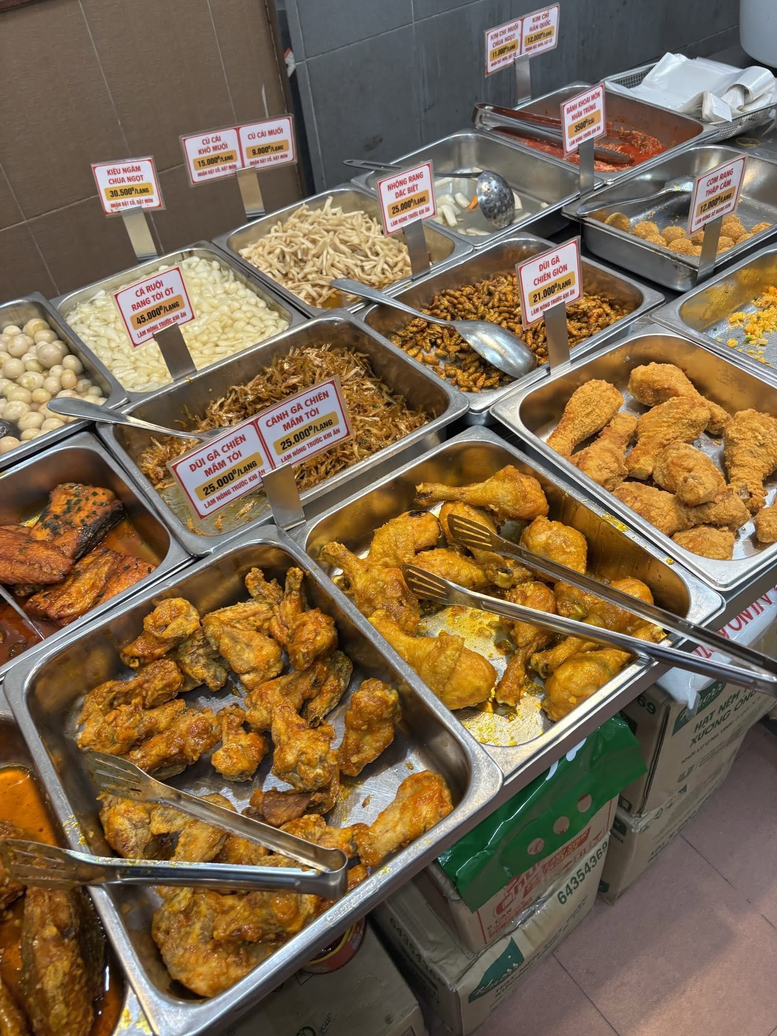 Món nào cũng đều được đựng trong khay lớn, sắp xếp gọn gàng, bên cạnh có ghi rõ tên món và giá bán để khách dễ lựa chọn. Nguồn: nhatlinh.th