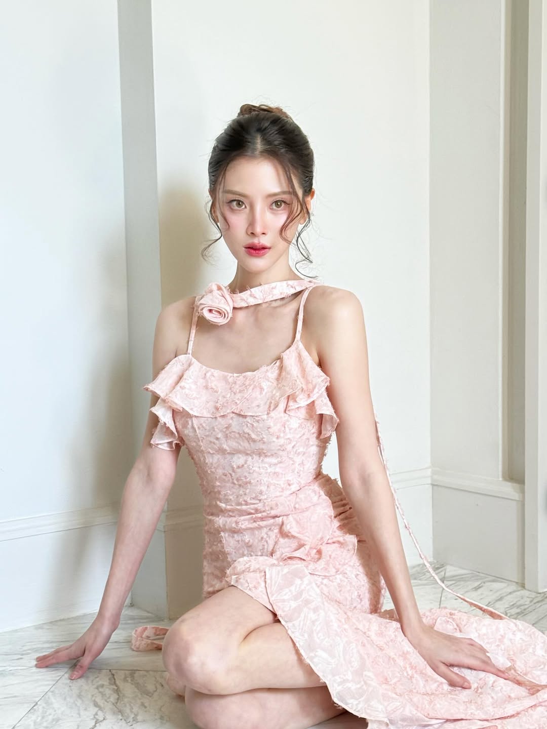 Baifern xinh mê mẩn khi diện mẫu váy hai dây màu hồng pastel ngọt ngào. Thiết kế ôm nhẹ tôn dáng kết hợp chi tiết bèo mềm mại giúp tổng thể trông vừa nữ tính vừa toát nét sang chảnh. Phần vạt quấn quanh cổ đính hoa là điểm nhấn hút mắt, giúp outfit càng thêm bay bổng và mềm mại