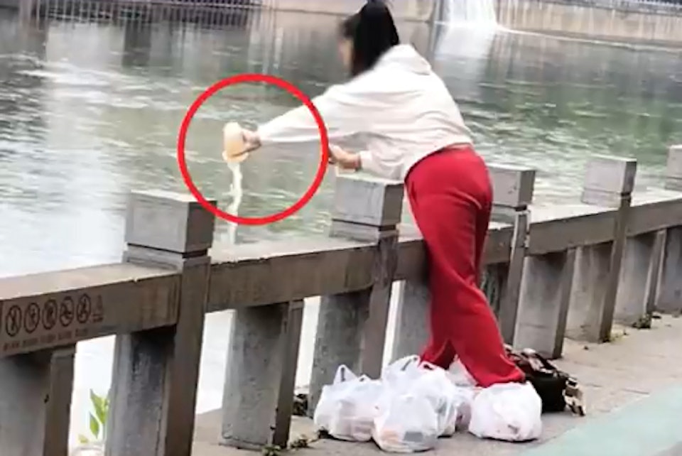 Người phụ nữ mở từng cốc rồi đổ hết xuống sông