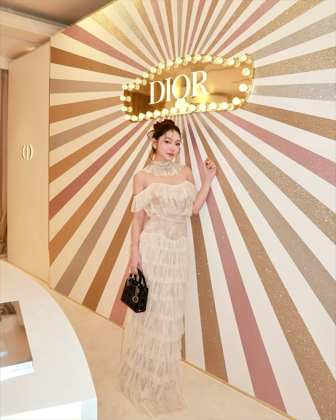 Hóa thân thành nàng thơ tại đêm tiệc Dior Ball, Chloe Nguyễn chọn một chiếc váy ren tầng của OnOn Made. Outfit là sự kết hợp giữa chất liệu ren được xếp lớp tỉ mỉ cùng cổ yếm voan nhún bèo, giúp người đẹp khoe khéo bờ vai mảnh. Điểm xuyết cùng chiếc túi Lady Dior, diện mạo all-white không chỉ tạo tổng thể vừa vặn với tinh thần Haute Couture của nhà mốt Pháp mà còn khẳng định khí chất sang trọng của Chloe. 