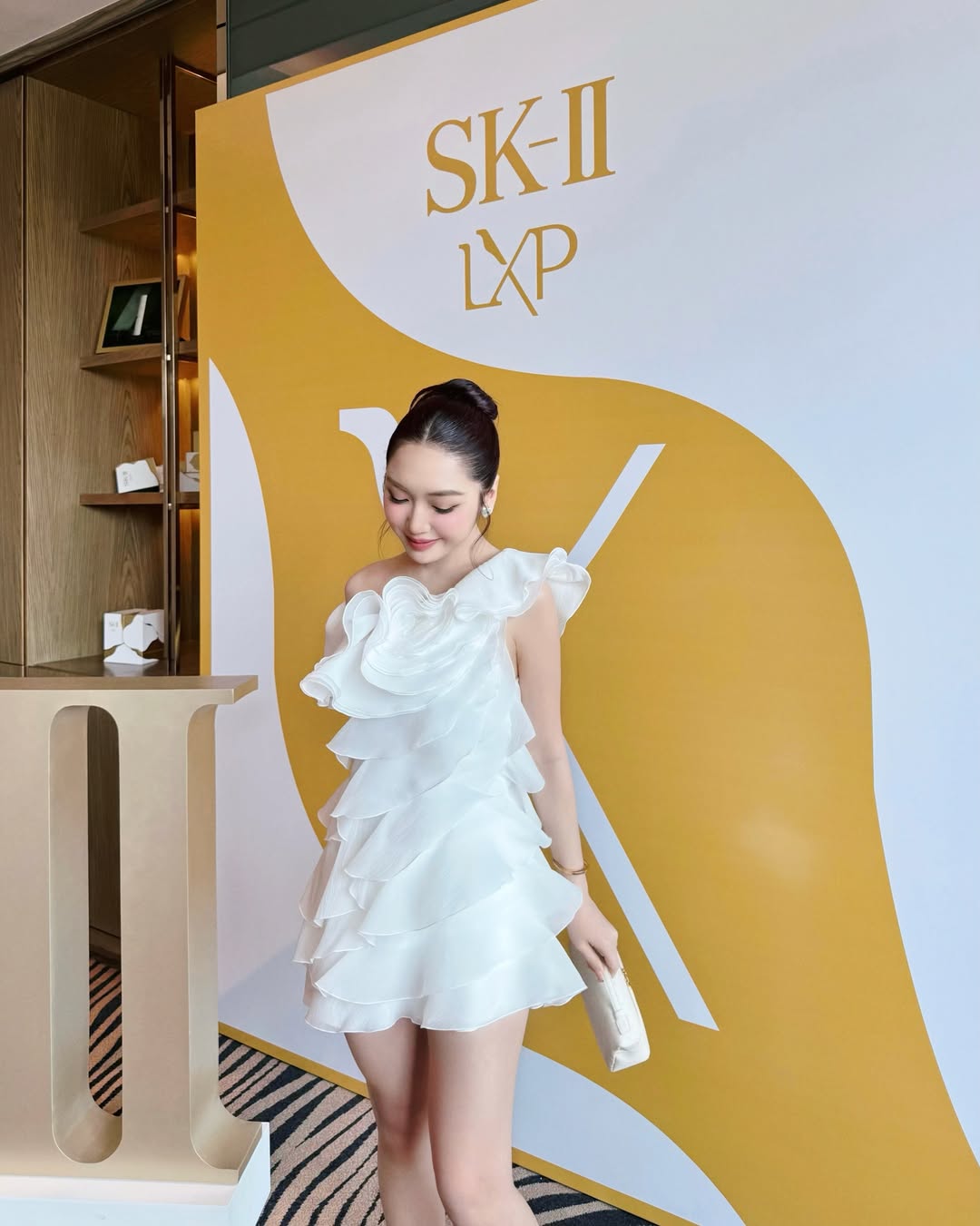 Ở một sự kiện khác, vẫn diện thiết kế của DATT, Chloe Nguyễn hóa thân thành một đóa bạch hồng trong sắc trắng thuần khiết. Chiếc váy ngắn lệch vai ghi điểm với chi tiết xếp nếp bèo nhún layer dọc thân váy, tạo hiệu ứng chuyển động bồng bềnh như những cánh hoa đang nở rộ. 