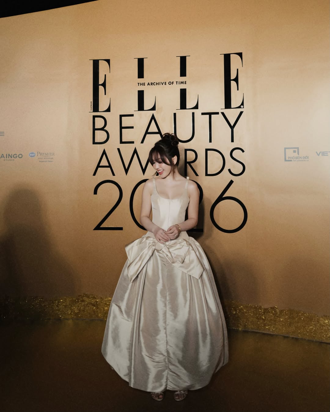 Xuất hiện trên thảm đỏ ELLE Beauty Awards, Chloe Nguyễn chiếm trọn spotlight với thiết kế đầm cúp ngực bồng bềnh mang sắc kem champagne thời thượng từ DAS LA VIE. Outfit này được xử lý tinh tế trên chất liệu taffeta, kết hợp phom dáng xếp nếp dựng khối để tái hiện diện mạo của một nàng công chúa bước ra từ thế giới cổ tích. Nhờ đó mà nàng tiểu thư tài phiệt toát lên trọn vẹn khí chất 