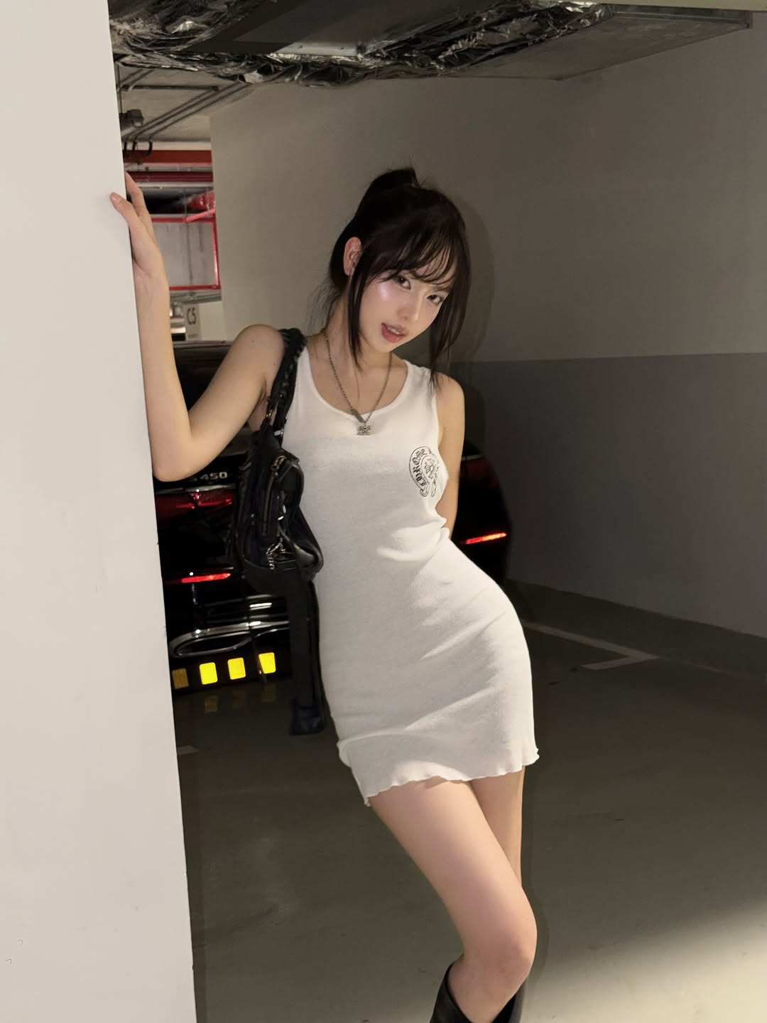 Outfit này của Thanh Thủy mang phong cách gợi cảm, cá tính. Cô diện chiếc váy ba lỗ ôm sát màu trắng giúp phô diễn trọn vẹn đường cong chữ S nóng bỏng. Sự tối giản của chiếc váy được cân bằng bằng các phụ kiện tông đen như chiếc túi xách hầm hố và đôi boot cổ cao, tạo tổng thể thời thượng, cuốn hút.