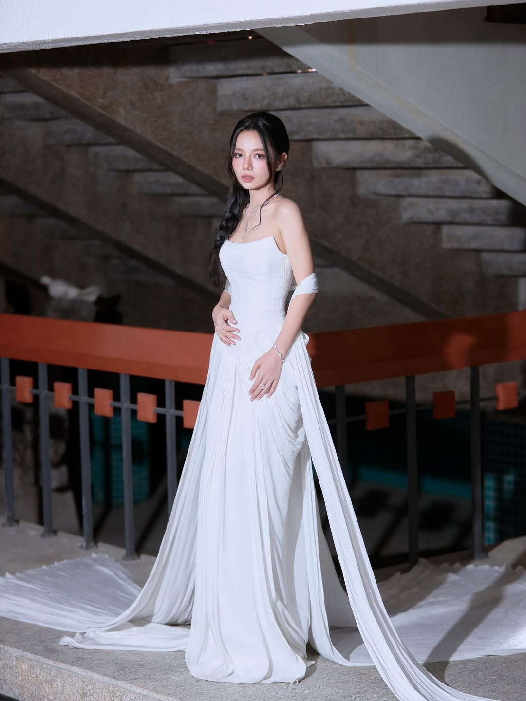 Mỹ nhân Mưa Đỏ tiếp tục chứng minh phong độ mặc đẹp khi diện thiết kế trắng tinh khôi đến từ Lecia Bridal. Mẫu đầm ôm sát phần thân trên, kết hợp chân váy rủ mềm cùng phần tà dài thướt tha giúp nữ diễn viên khoe trọn vóc dáng mảnh mai và bờ vai thanh thoát. Không lựa chọn phụ kiện cầu kỳ, cô chỉ nhấn nhá bằng trang sức tối giản và kiểu tóc tết lệch nữ tính, trông như một nàng nữ thần Hy Lạp chất thơ.
