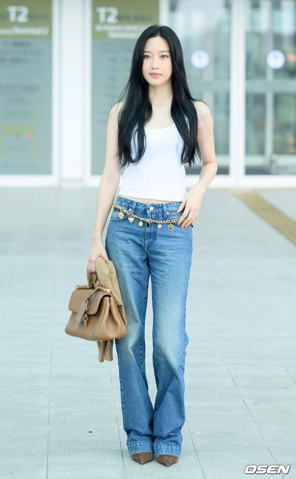 Màu sắc hơn, Moon Ga Young chọn áo tank top trắng basic kết hợp quần jeans ống đứng wash xanh nhẹ nhàng. Cô phối cùng belt xích và phụ kiện giày - túi nâu đồng điệu để outfit thêm điểm nhấn.