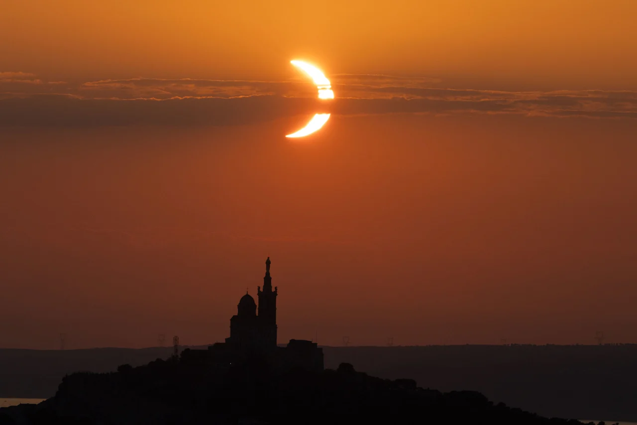 Mặt trăng khuất sau đường chân trời của mặt trời, phía sau nhà thờ Notre-Dame de la Garde ở Marseille, Pháp. Ảnh: AFP qua Getty Images
