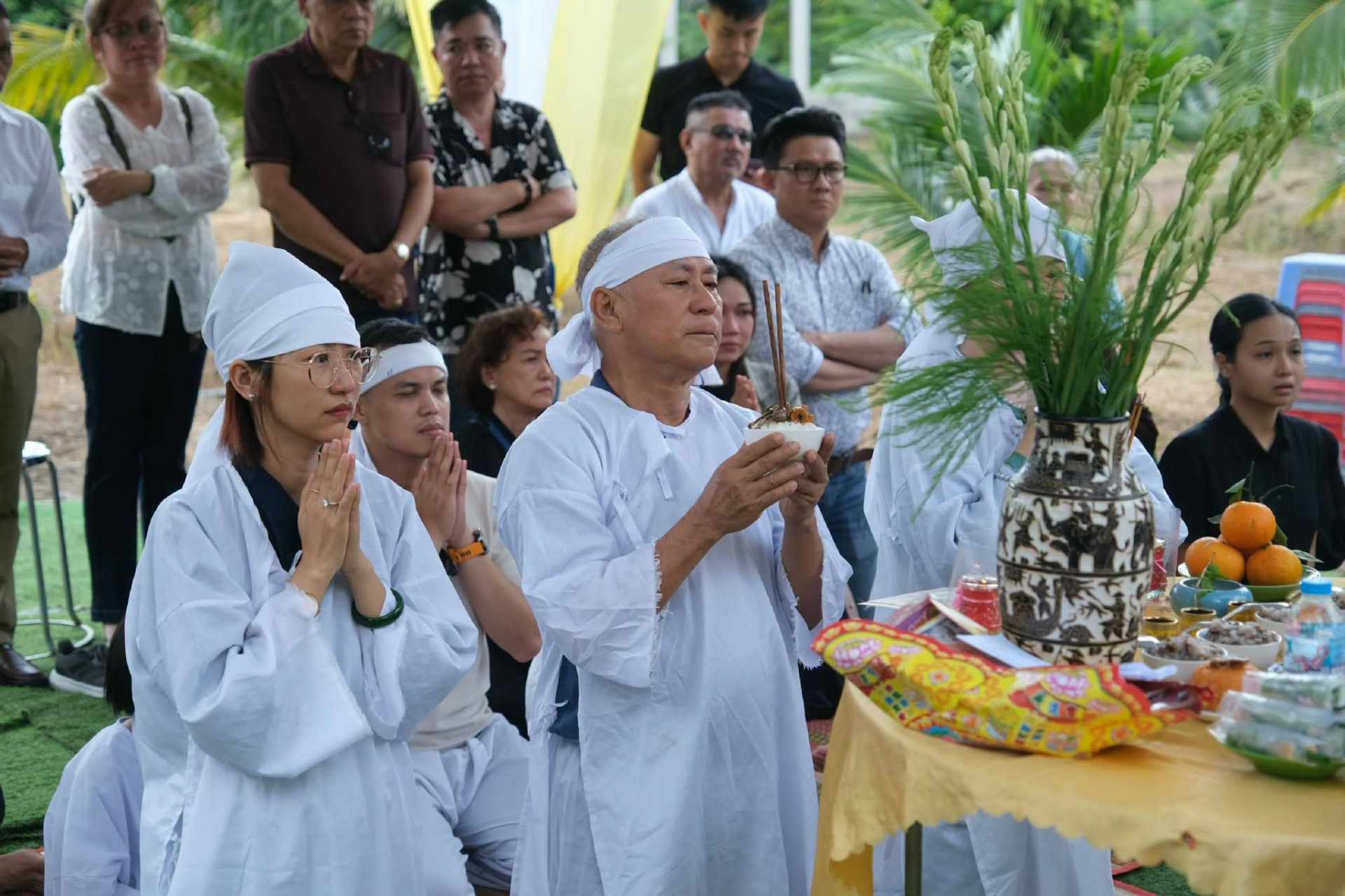 NSND Tạ Minh Tâm cùng người thân thực hiện nghi thức trước phần mộ của vợ. Ảnh: FBNV