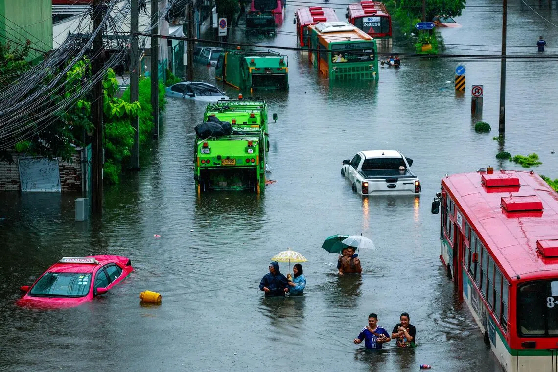 Người dân lội qua con phố ngập nước trong trận mưa lớn ở Bangkok ngày 26 tháng 9 (ẢNH: REUTERS)