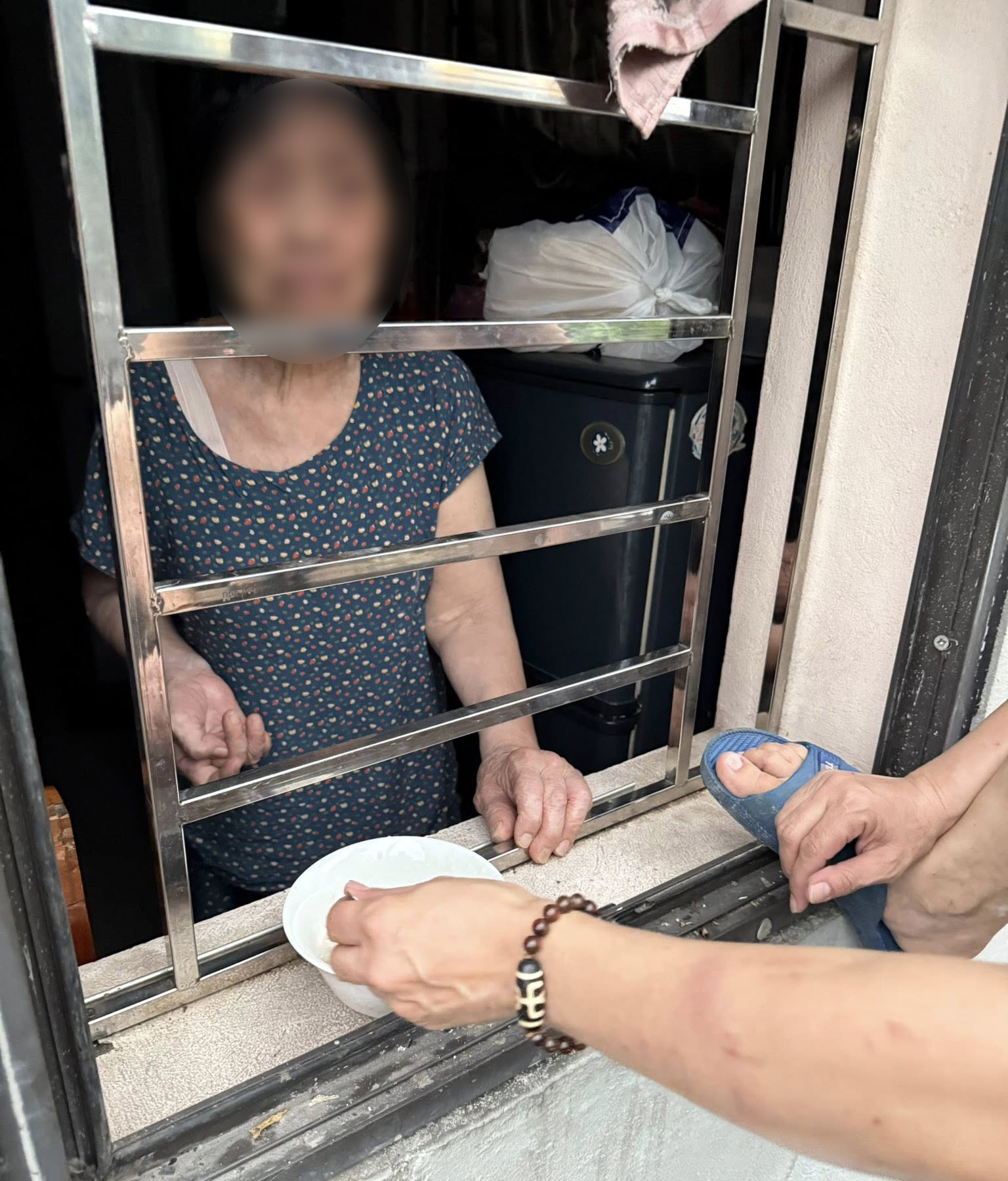 Người thân đưa cơm cho cụ bà qua cửa sổ.