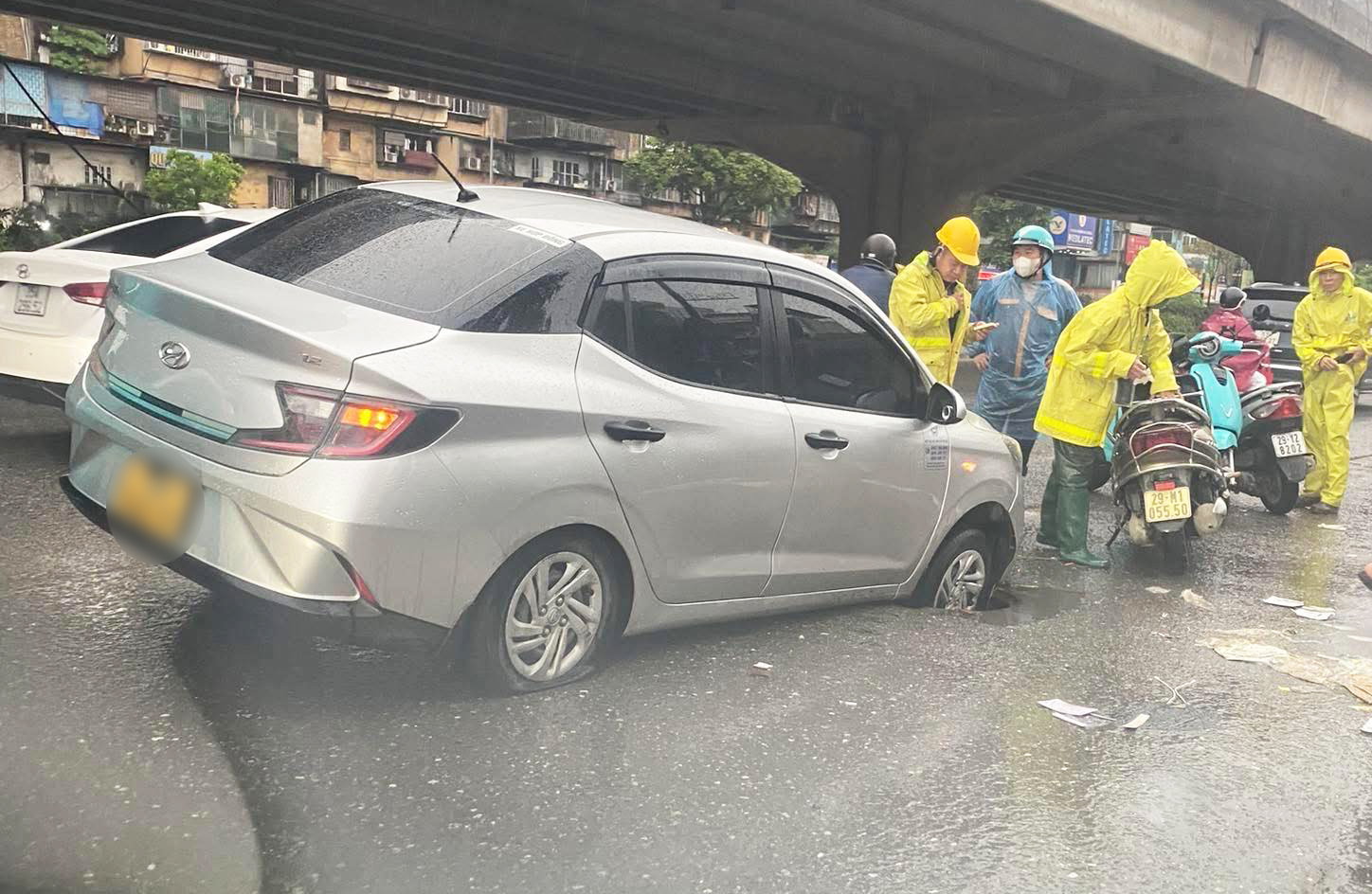 Chiếc taxi bị tụt bánh xuống cống, xảy ra tại đường Khuất Duy Tiến sáng 24/4. 