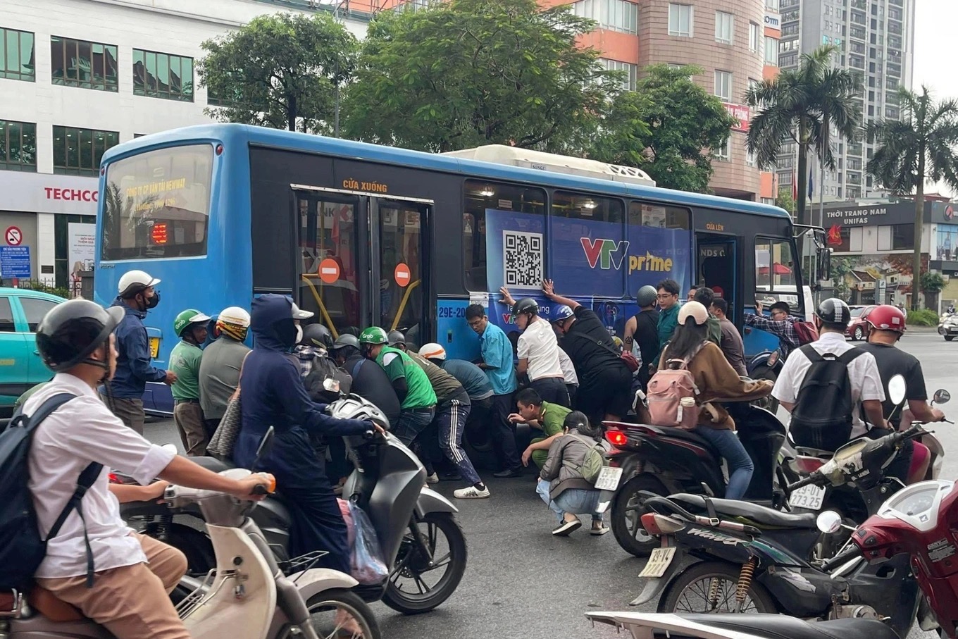 Lực lượng chức năng cùng hàng chục người dân hỗ trợ nâng xe buýt cứu nạn nhân mắc kẹt. (Ảnh: Tuổi Trẻ Online)