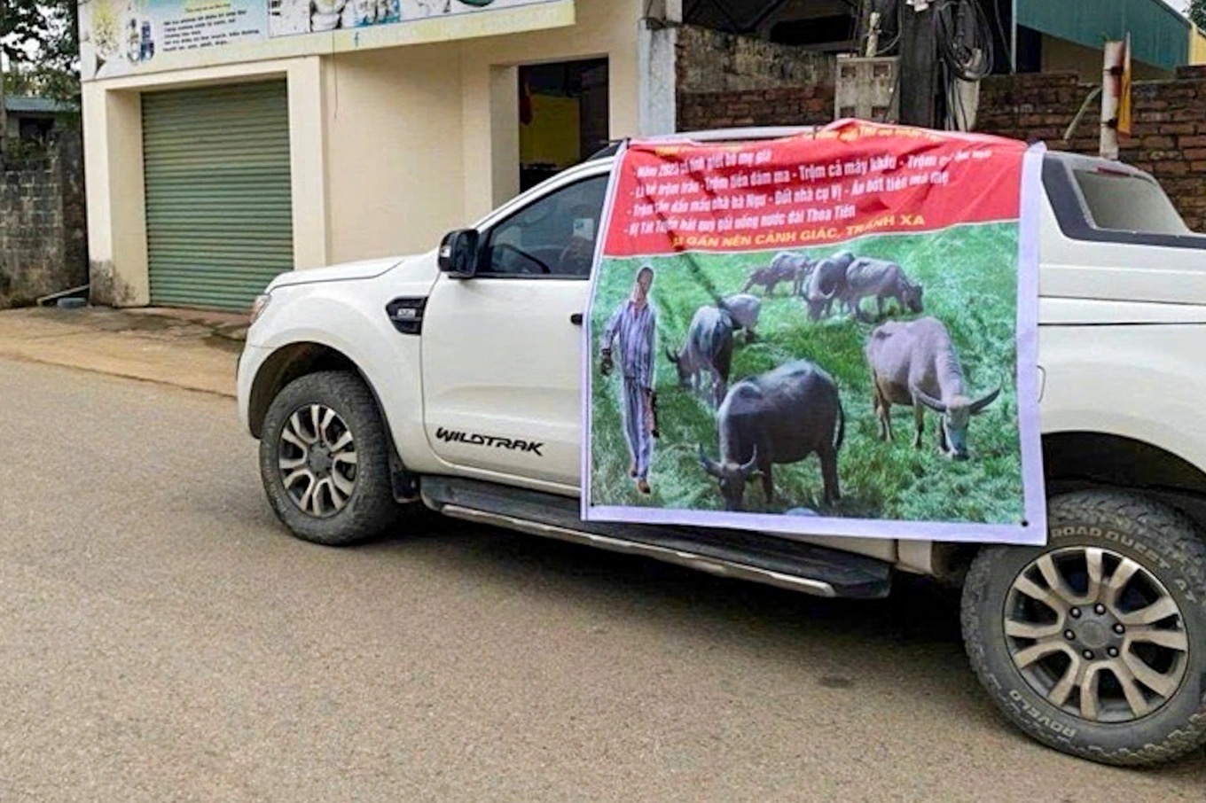 Ông Đích bị nhóm người in băng rôn, dán lên xe bán tải rồi phát loa khắp làng để bêu riếu. (Ảnh: Dân trí)