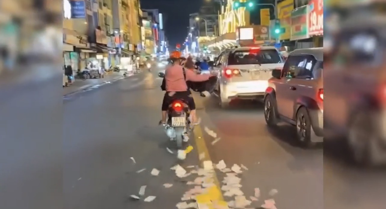 Bà G. bất ngờ tung bọc giấy tiền to ra giữa đường ở TP.HCM. (Ảnh: Cắt từ clip)