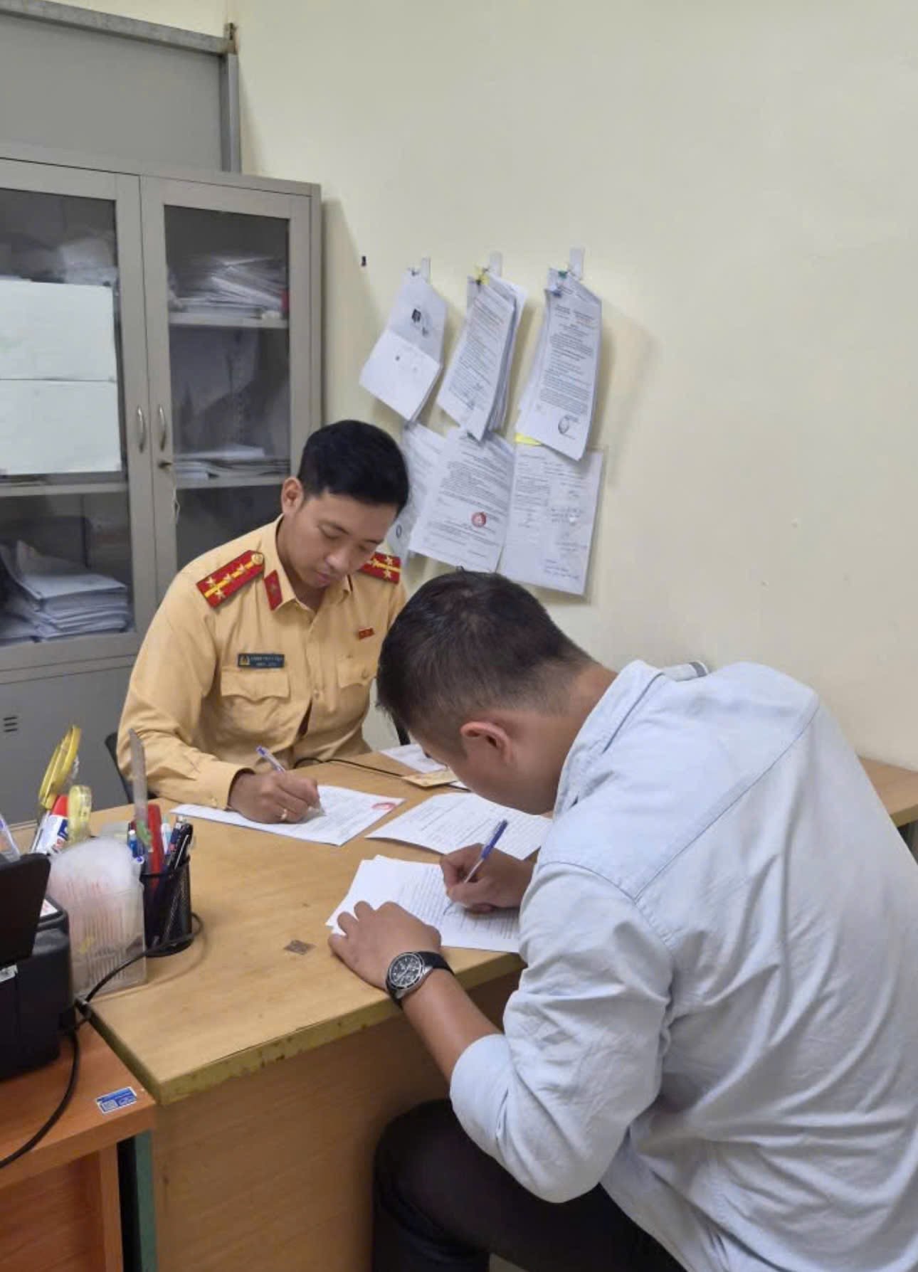 Nam thanh niên vừa dùng điện thoại vừa điều khiển xe máy làm việc tại cơ quan chức năng. (Nguồn: Cục Cảnh sát giao thông)