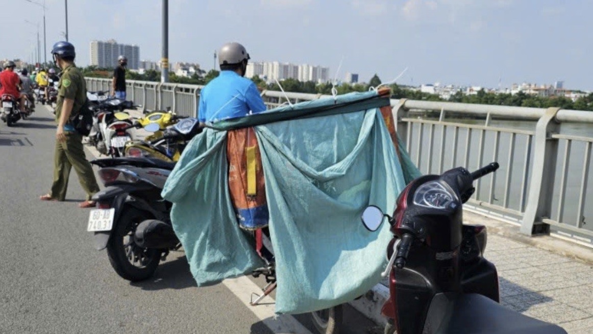 Hiện trường nơi nam shipper để lại xe máy cùng thùng hàng, nhảy xuống sông mất tích. (Ảnh: Pháp luật TP.HCM)