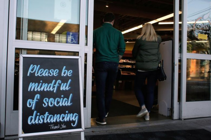 Tấm biển nhắc nhở khách hàng hãy chú ý giữ khoảng cách xã hội ở một cửa hàng tại Seattle, Washington.