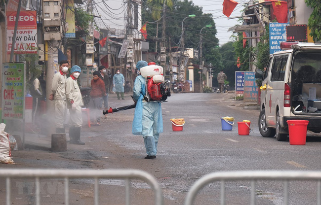 Lực lượng chức năng phun khử khuẩn tại thôn Hạ Lôi, Mê Linh. Ảnh: TTXVN