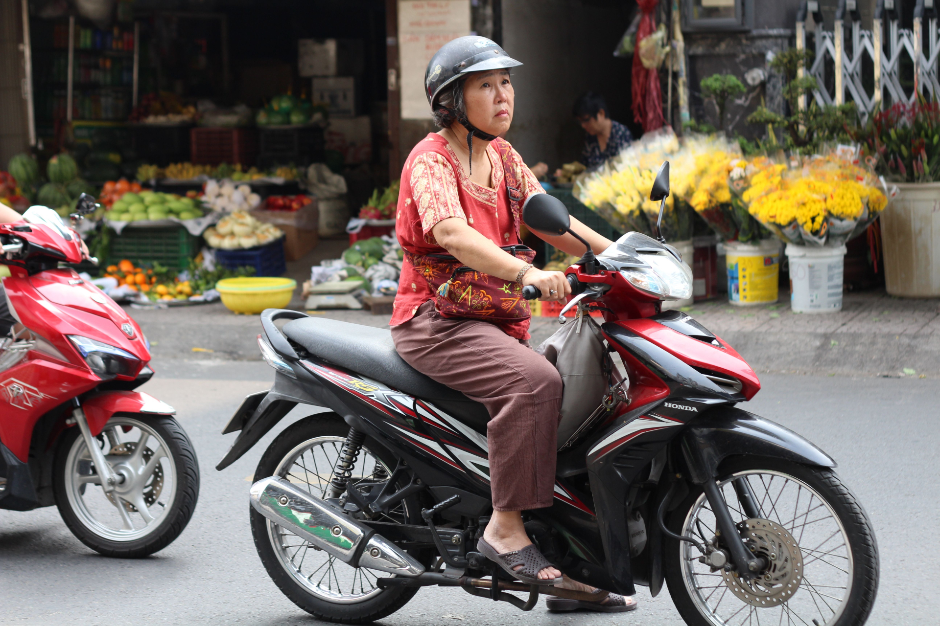 Một phụ nữ đi xe máy qua khu chợ tại Sài Gòn. Ảnh minh họa: Kushie In Vietnam/Pexels.