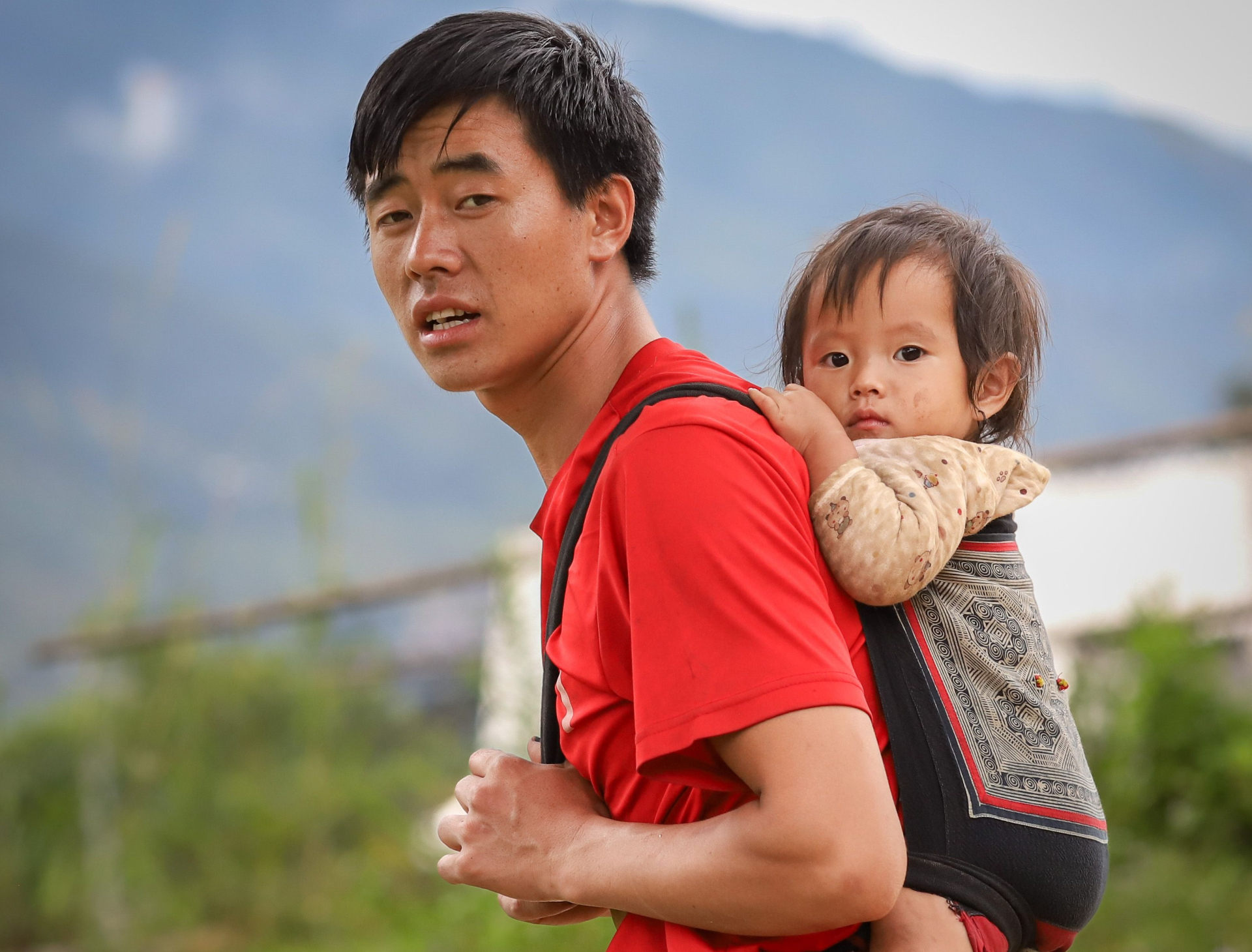 Một người cha địu con trong sinh hoạt thường ngày tại Lào Cai. Việc chăm sóc con không phải trách nhiệm mặc định của riêng người mẹ. Ảnh minh họa: Son Hoa Nguyen/Pexels.