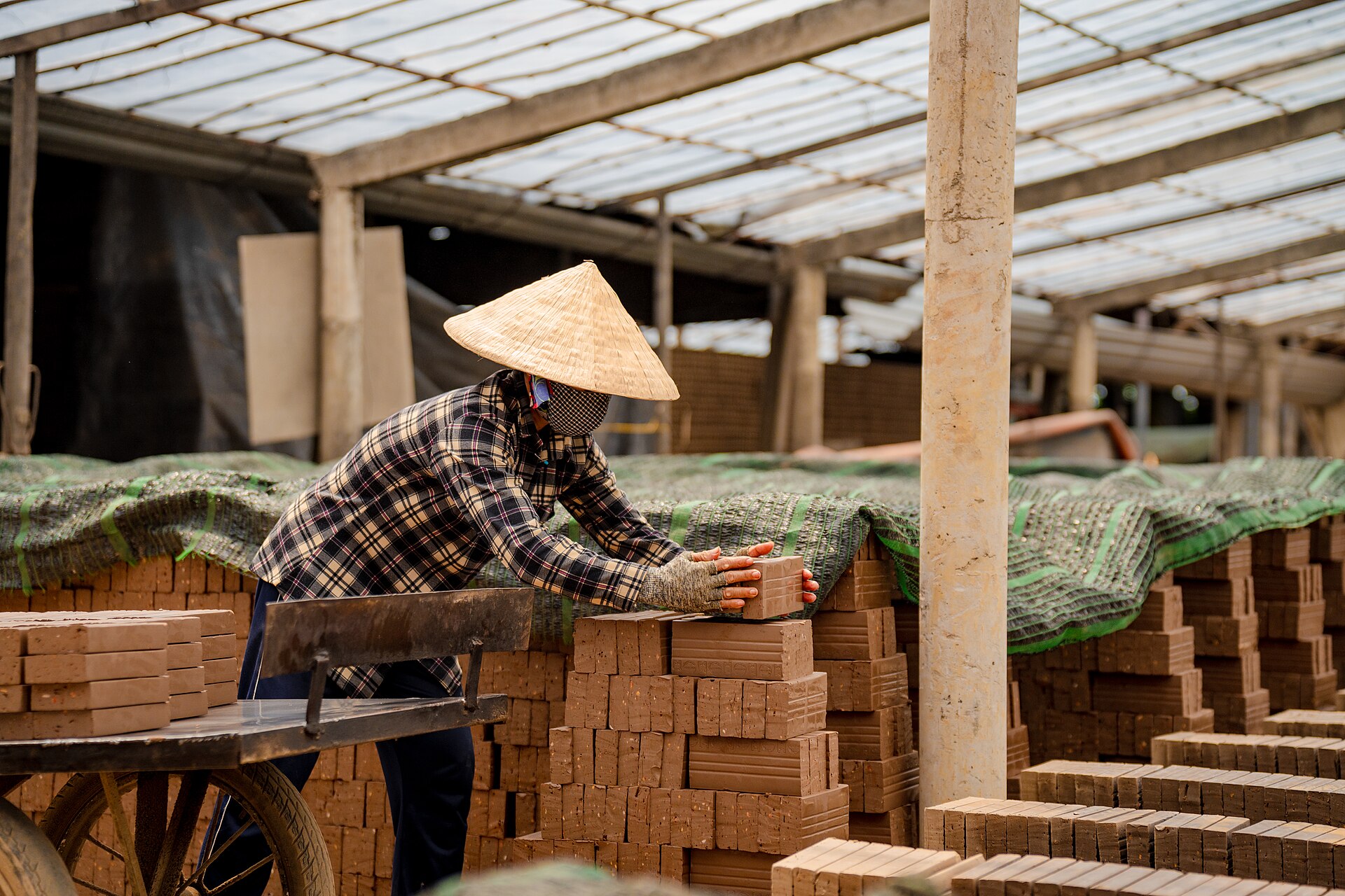 Một phụ nữ phơi gạch dưới nắng tại Vĩnh Long. Tải nhiệt tại nơi làm việc phụ thuộc đồng thời môi trường và cường độ công việc. Ảnh: Tuong Lam Photos/Wikimedia Commons, CC BY-SA 4.0.
