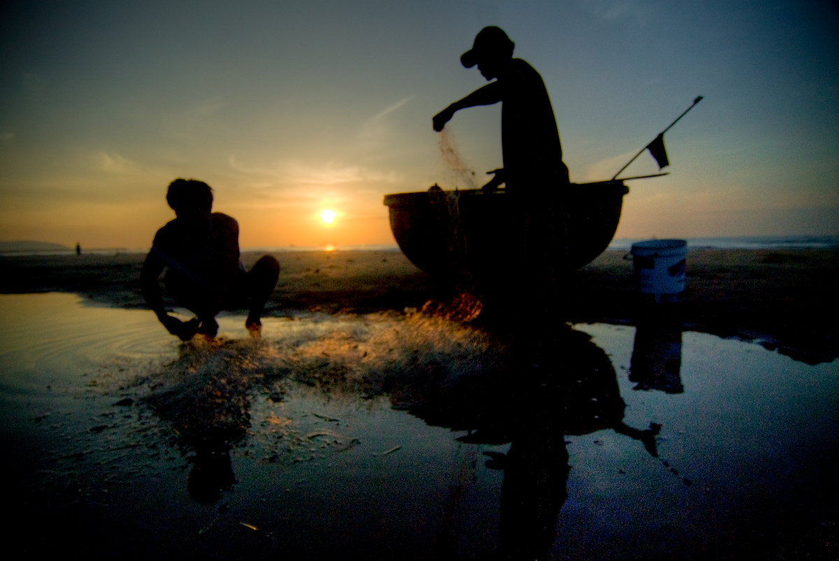 Hai ngư dân làm việc với lưới trên bãi biển Phan Thiết vào sáng sớm. Nghề cá là một trong các nhóm lao động thủ công được WHO/WMO lưu ý khi đánh giá nguy cơ nhiệt. Ảnh: Lucas Jans/Wikimedia Commons, CC BY-SA 2.0.