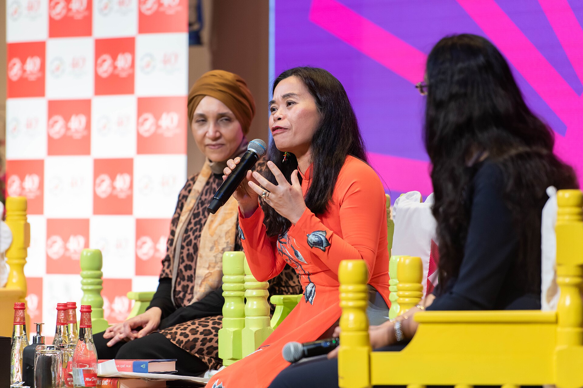 TS Nguyễn Phan Quế Mai (giữa, áo dài cam) phát biểu tại một phiên thảo luận của Emirates Airline Festival of Literature năm 2024. Ảnh: Shahdmurshed/Wikimedia Commons, CC BY-SA 4.0