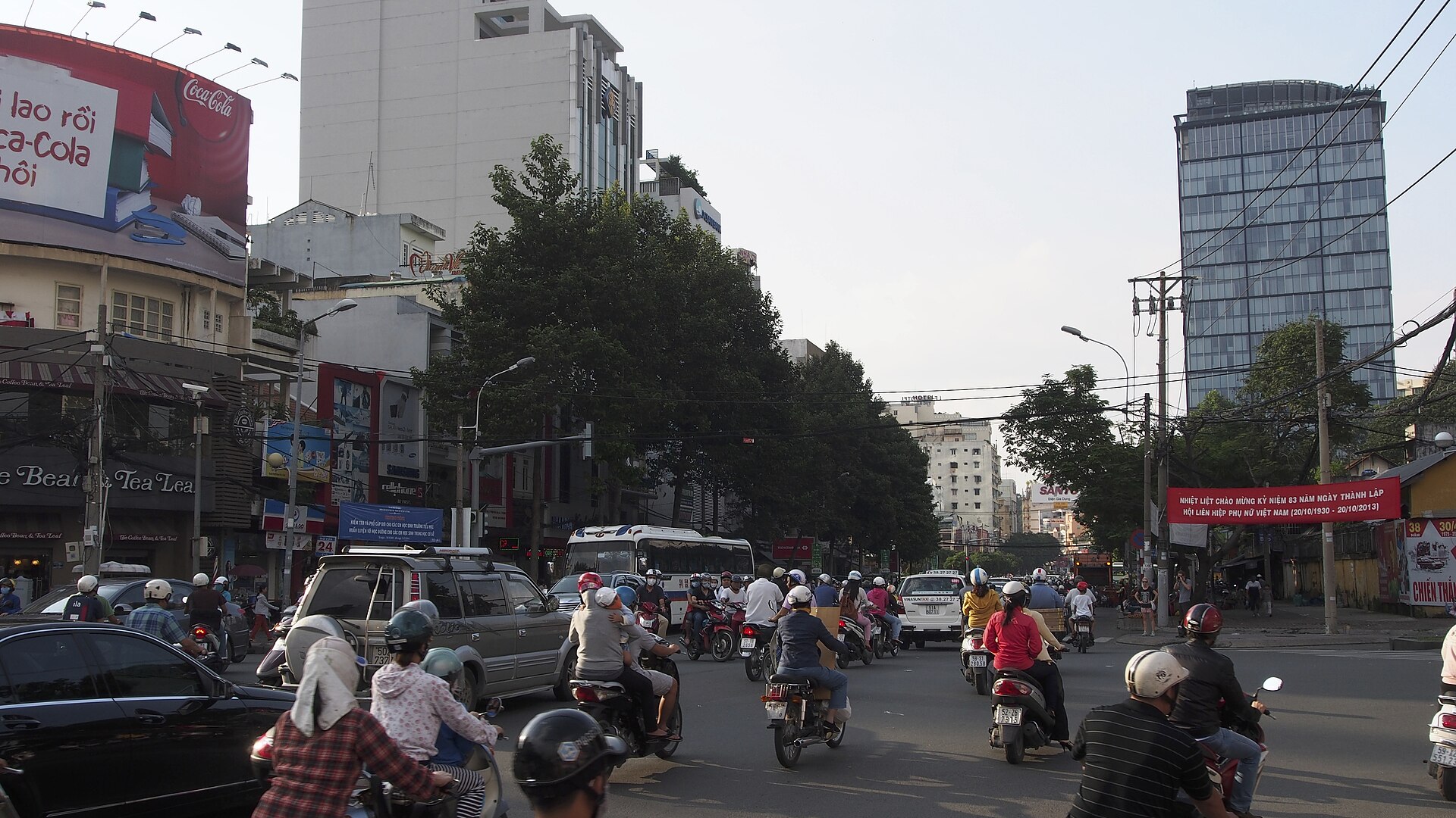 Người đi bộ qua đường giữa dòng xe tại TP.HCM. Một chu kỳ đèn phù hợp cần tính cả thời gian khởi bước, bề rộng đường và xung đột với xe rẽ. Ảnh: Clay Gilliland/Wikimedia Commons, CC BY-SA 2.0.