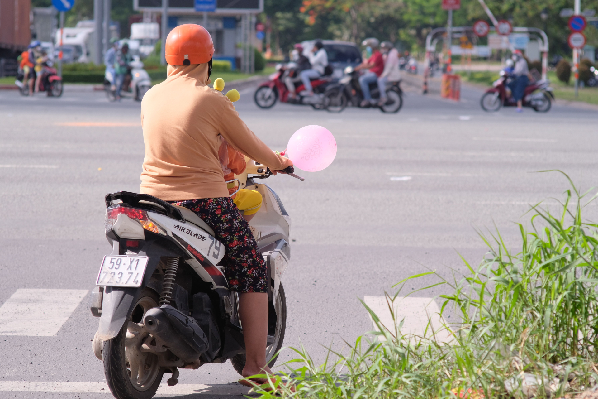 Một phụ nữ chở trẻ em bằng xe máy tại Việt Nam. Việc đưa đón thành viên gia đình là một trong những hoạt động có thể tạo thêm chặng trong hành trình hằng ngày. Ảnh minh họa: Nguyen Huy/Pexels.