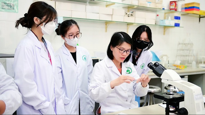 PGS.TS Nguyễn Thị Thu Hoài trao đổi với sinh viên trong phòng thí nghiệm vi sinh. Ảnh: VTC News.