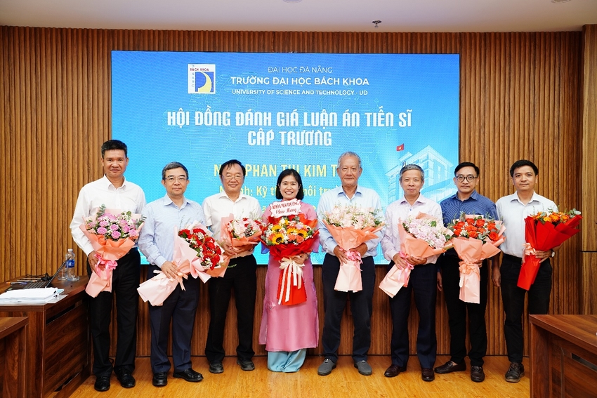 NCS. Phan Thị Kim Thủy, đứng giữa cầm hoa, cùng Hội đồng đánh giá luận án tiến sĩ ngành Kỹ thuật môi trường ngày 4/7/2026. Ảnh: Trung tâm Học liệu và Truyền thông, Trường Đại học Bách khoa - Đại học Đà Nẵng.