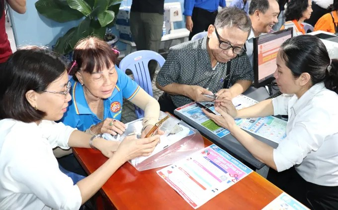 Cán bộ tại phường Bình Quới, TP.HCM hướng dẫn người cao tuổi sử dụng ứng dụng trên điện thoại tại khu dân cư. Ảnh: Thái Phương/Cổng Thông tin điện tử Thành ủy TP.HCM.