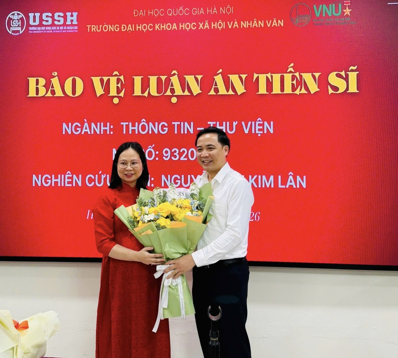 NCS. Nguyễn Thị Kim Lân tặng hoa tri ân PGS.TS. Đỗ Văn Hùng, Chủ tịch Hội đồng đánh giá luận án, sau buổi bảo vệ ngày 16/4/2026. Ảnh: Khoa Quản trị thông tin, Trường Đại học Khoa học Xã hội và Nhân văn.