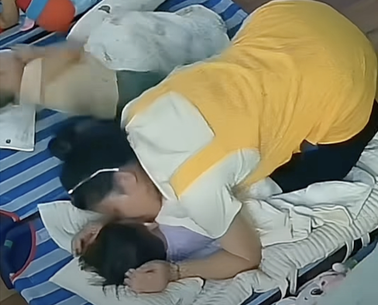 Với một bé trai nằm thao thức chưa ngủ được, cô cúi xuống ôm nhẹ, vỗ về rồi hôn lên má đứa trẻ như một cách dỗ dành rất tự nhiên. (nguồn: Gia đình Khoai Hiểu Minh)
