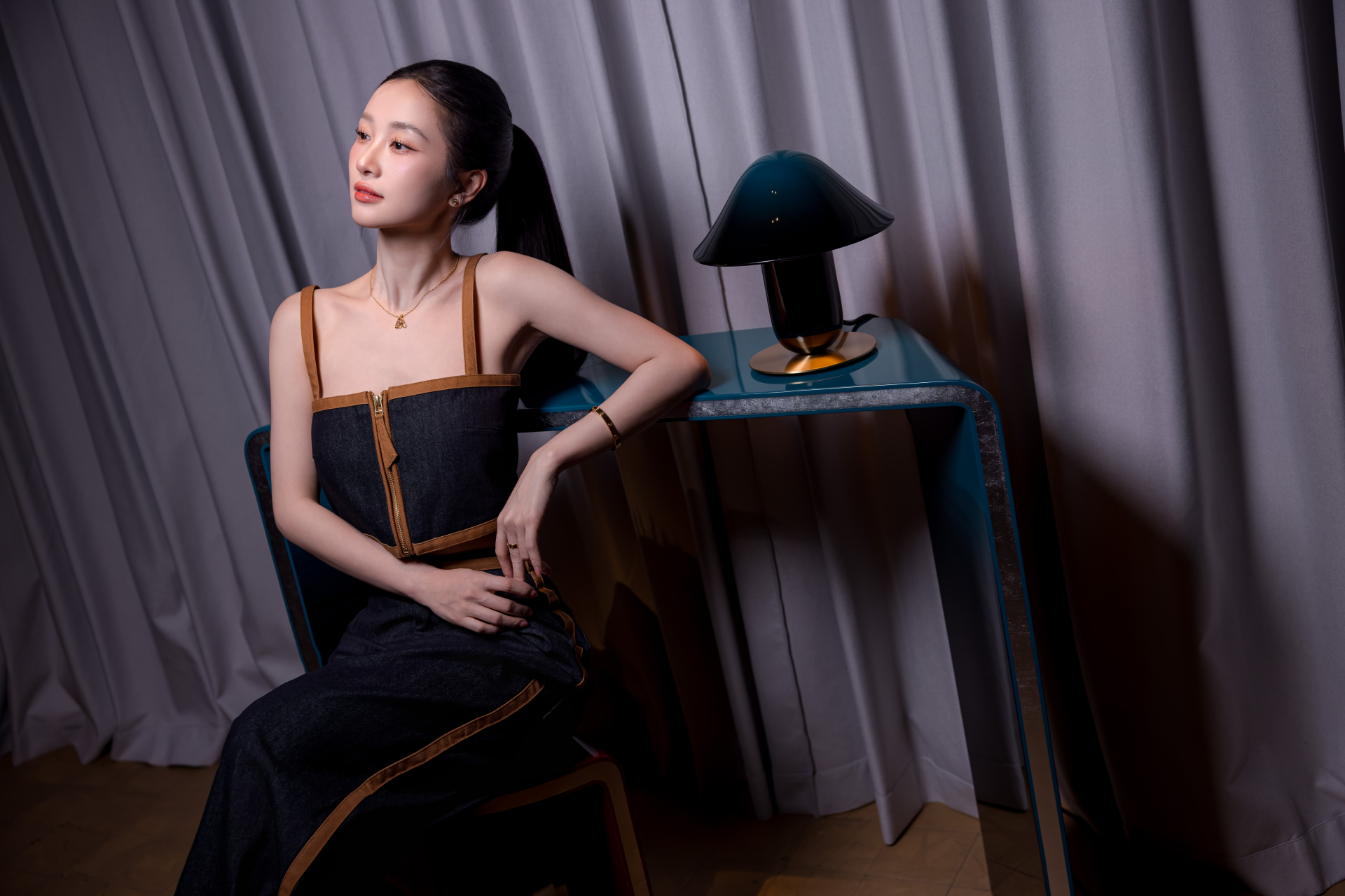 Jun Vũ tạo dáng bên bộ bàn và đèn sơn mài tông xanh cổ vịt, ánh bạc kim loại. Ảnh: Hanoia